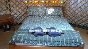 A bed with a checkered bedspread, pillows, and a headboard with hanging lights.