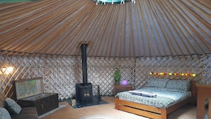 A cozy room with a bed, a sofa, a small table, a map, and a wood-burning stove.