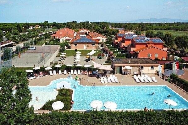 Um resort com uma grande piscina, espreguiçadeiras e vista para a paisagem ao redor.