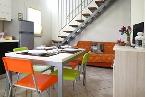 Um espaço compacto com área de refeições, cozinha compacta, sofá e escada.