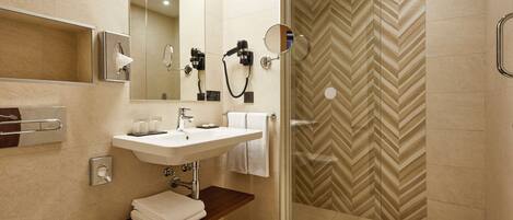 A modern bathroom with a glass-enclosed shower, a sink with a mirror, and a towel rack.