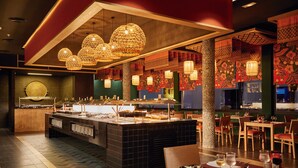 Un restaurant doté d’un buffet, de plusieurs tables et de lampes en osier suspendues au plafond.