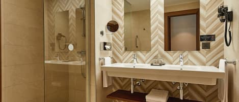 Un baño moderno con ducha de vidrio, tocador doble y espejo sobre el lavamanos.