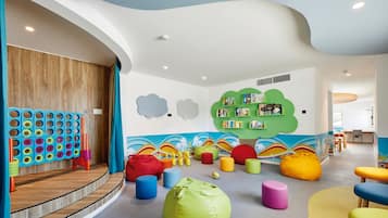 Een kinderspeelruimte met kleurrijk meubilair en een muur met wolkenversieringen.