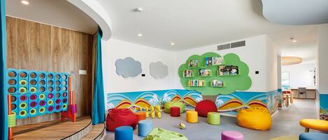 A children's play area with colorful furniture and a wall with cloud decorations.