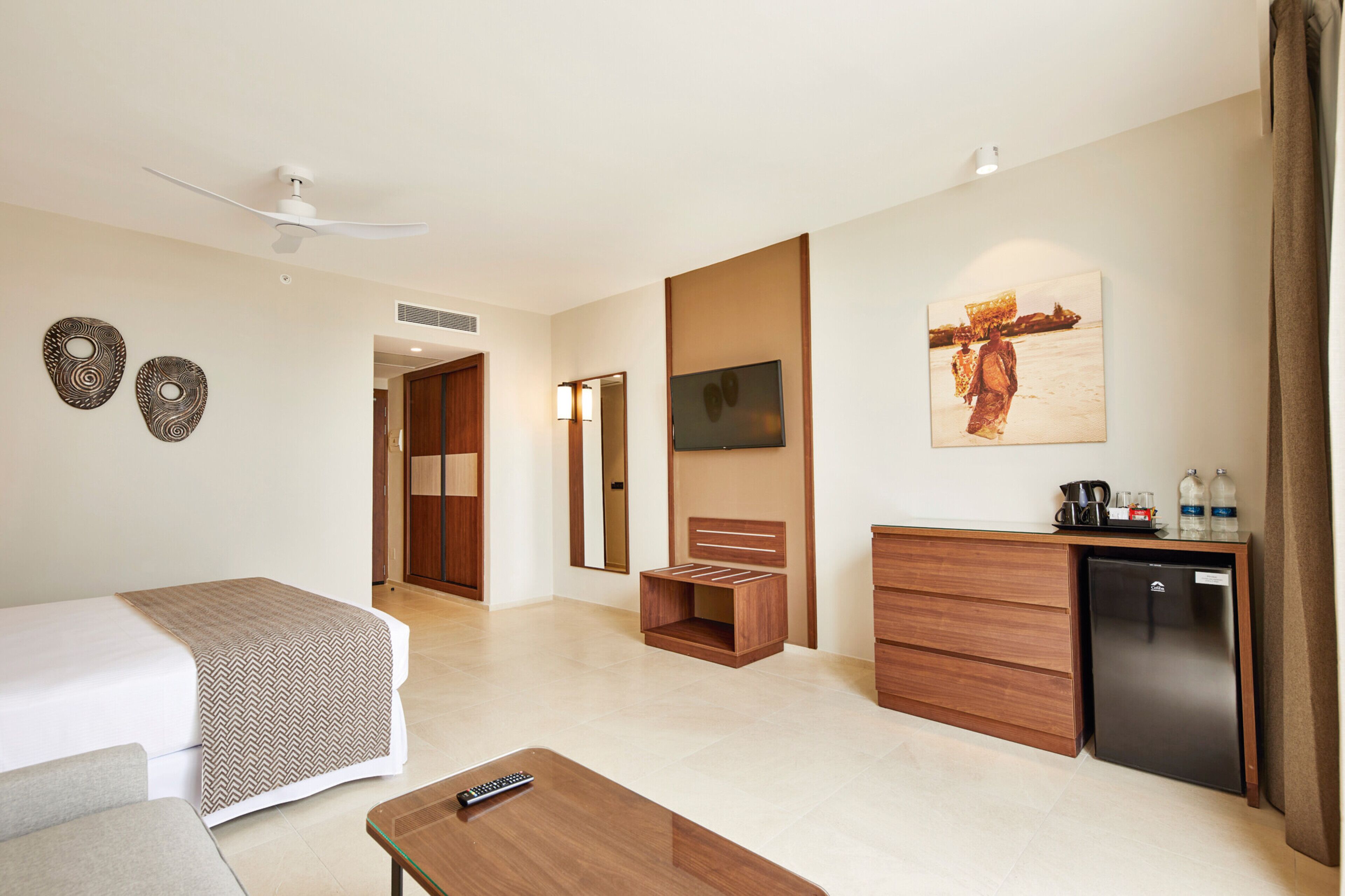 A hotel room with a bed, a desk, a TV, a mirror, and a wardrobe.