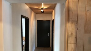 A narrow hallway with wooden flooring, white walls, and a ceiling fan. A black door is visible at the end of the hallway. - Apartment with mountain view | skiing & hiking area | near Mölltaler Gletscher (Mallnitz)