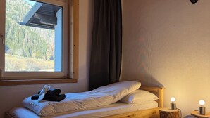 Una cama de madera en una habitación con ventana, una decoración de cabeza de ciervo en la pared y dos lámparas de noche.