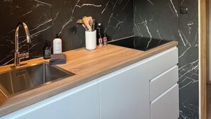 Una cocina moderna con salpicadero de mármol negro, pileta de acero inoxidable y encimera de madera.