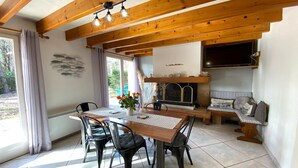 Un comedor con mesa y sillas de madera, una chimenea y un televisor montado en la pared.