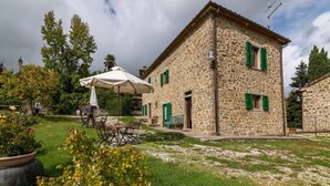 Un bâtiment en pierre doté d’un patio avec jardin, d’un espace extérieur aménagé pour s’asseoir et d’un grand parasol.