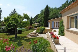 Una casa con jardín, un patio y un camino que lleva a la entrada.