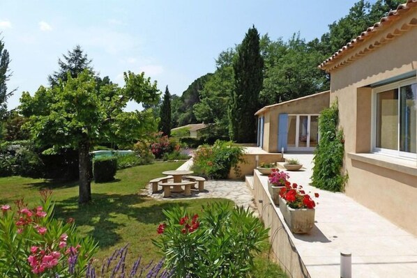 A house with a garden, a patio, and a pathway leading to the entrance.