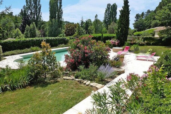 Una piscina rodeada de exuberante vegetación y un jardín bien cuidado.
