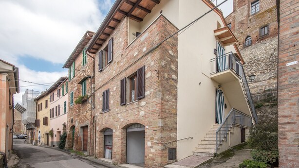 Une rue étroite bordée de bâtiments traditionnels, caractérisée par des portes en arc de cercle et des balcons en bois.