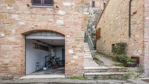 Une ruelle étroite avec un bâtiment en briques, un vélo et un tonneau en bois.