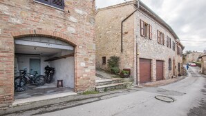 Une rue étroite bordée de vieux bâtiments, un vélo garé devant l’un d’eux, et une personne qui marche au loin.