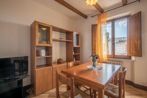 A dining area with a wooden table, chairs, a TV, and built-in wooden cabinets.