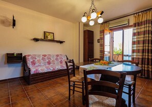 Zona pranzo con tavolo, sedie, divano e lampadario.