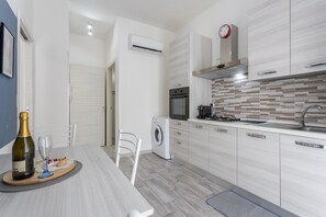 A modern kitchen with a built-in oven, a washing machine, and a dining area with a table set for two.