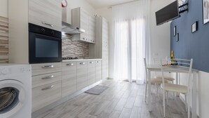 Una cocina moderna con horno empotrado, lavadora y comedor con mesa y sillas.
