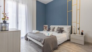 Un dormitorio con cama, mesita de noche, lámpara y ventana con cortinas.