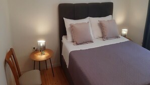 Een slaapkamer met een bed, twee bedlampen, een houten stoel en een kleine tafel.