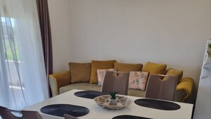Een moderne woonkamer met een bank, stoelen, een eettafel en een luchtverkoeler aan het plafond.