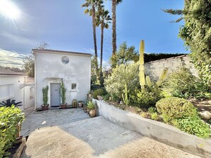 A small building with a door and window, surrounded by various plants and cacti. - Charming Duplex Studio in Porticcio with Terrace, Close to Beaches and Airport (Porticcio)