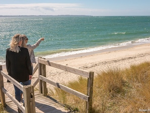 A wooden boardwalk leading to a beach with a view of the ocean.
