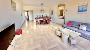 A modern living room with a sofa, coffee table, TV, and dining area. - Ajaccio: Air-conditioned 4-room apartment, 6 beds, downtown (Ajaccio)