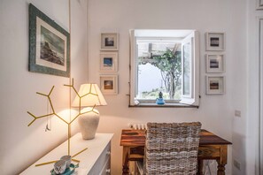 Habitació amb taula, cadira, làmpada i finestra que dona a zones verdes.