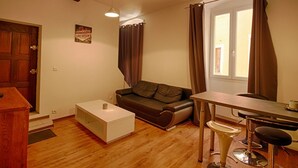 Un ambiente compatto con divano, un piccolo tavolo e un angolo bar.