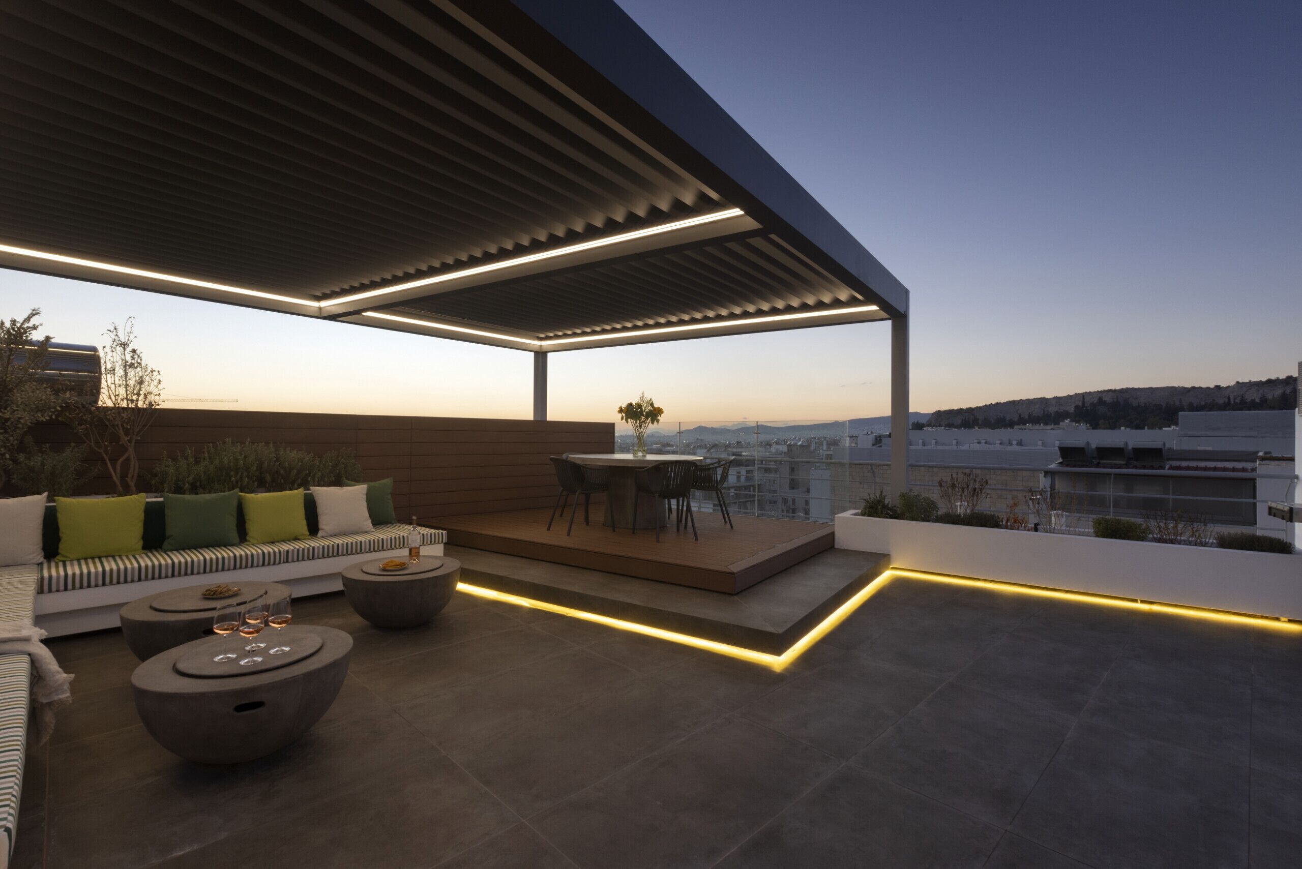 Zona relax esterna moderna con divano, tavolini rotondi e vista sulla città.