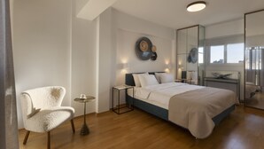 Een moderne slaapkamer met een bed, een stoel, een klein tafeltje en een grote spiegel.