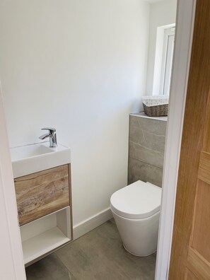 Une petite salle de bain moderne avec un lavabo blanc, un meuble en bois et des toilettes blanches.