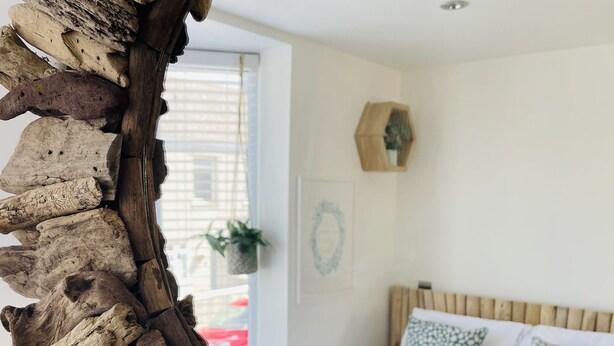 A room with a bed, a wooden headboard, a wall-mounted hexagonal shelf, and a framed picture.