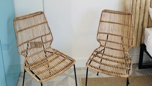 Two wicker chairs with black metal legs, a macrame wall hanging, and a blue wall.