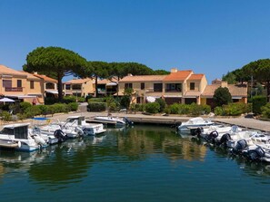 Uma marina com vários barcos atracados, rodeada por edifícios residenciais com telhados em cerâmica e varandas.