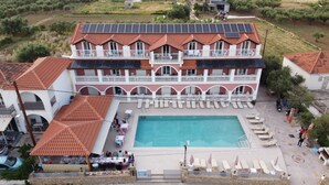 A large building with a swimming pool, multiple balconies, and solar panels. - Giannis Studios Alykes (Zakynthos)