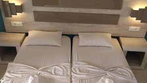 A double bed with white linens and towels, wooden headboard with built-in lighting, and a teal wall. - Giannis Studios Alykes (Zakynthos)