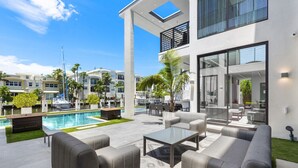 A modern outdoor pool area with a lounge setup, including sofas and a coffee table. - Boardwalk Mansion Lauderdale Villa: Private Pool, Hot Tub, Mini-Golf & Guest House (Fort Lauderdale)