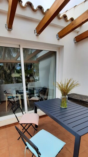 A patio area with a table and chairs, a glass door leading to an indoor space, and a potted plant.