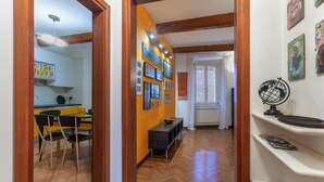 A hallway with wooden beams, a dining area with chairs and a table, and a wall with framed pictures. - GuestHost - Central Ferrara Apartment! x7 (Ferrara)