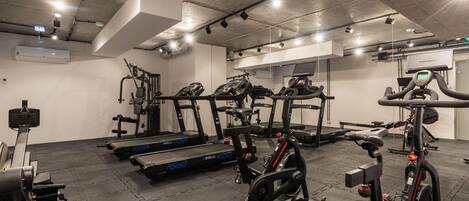 A gym with various exercise equipment including treadmills, stationary bikes, and weight machines.