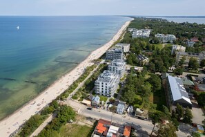 Une vue aérienne d’une zone côtière avec une plage, des bâtiments et une route.