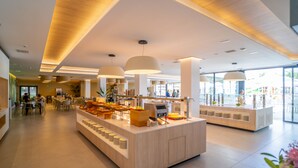A modern hotel lobby with a central counter, seating area, and large windows. - Alannia Salou Resort  (Salou)