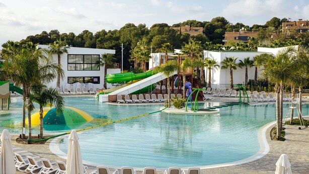 A swimming pool with a water slide, lounge chairs, and palm trees. - Alannia Salou Resort  (Salou)