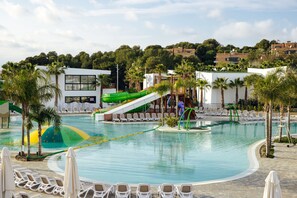 A swimming pool with a water slide, lounge chairs, and palm trees. - Alannia Salou Resort  (Salou)