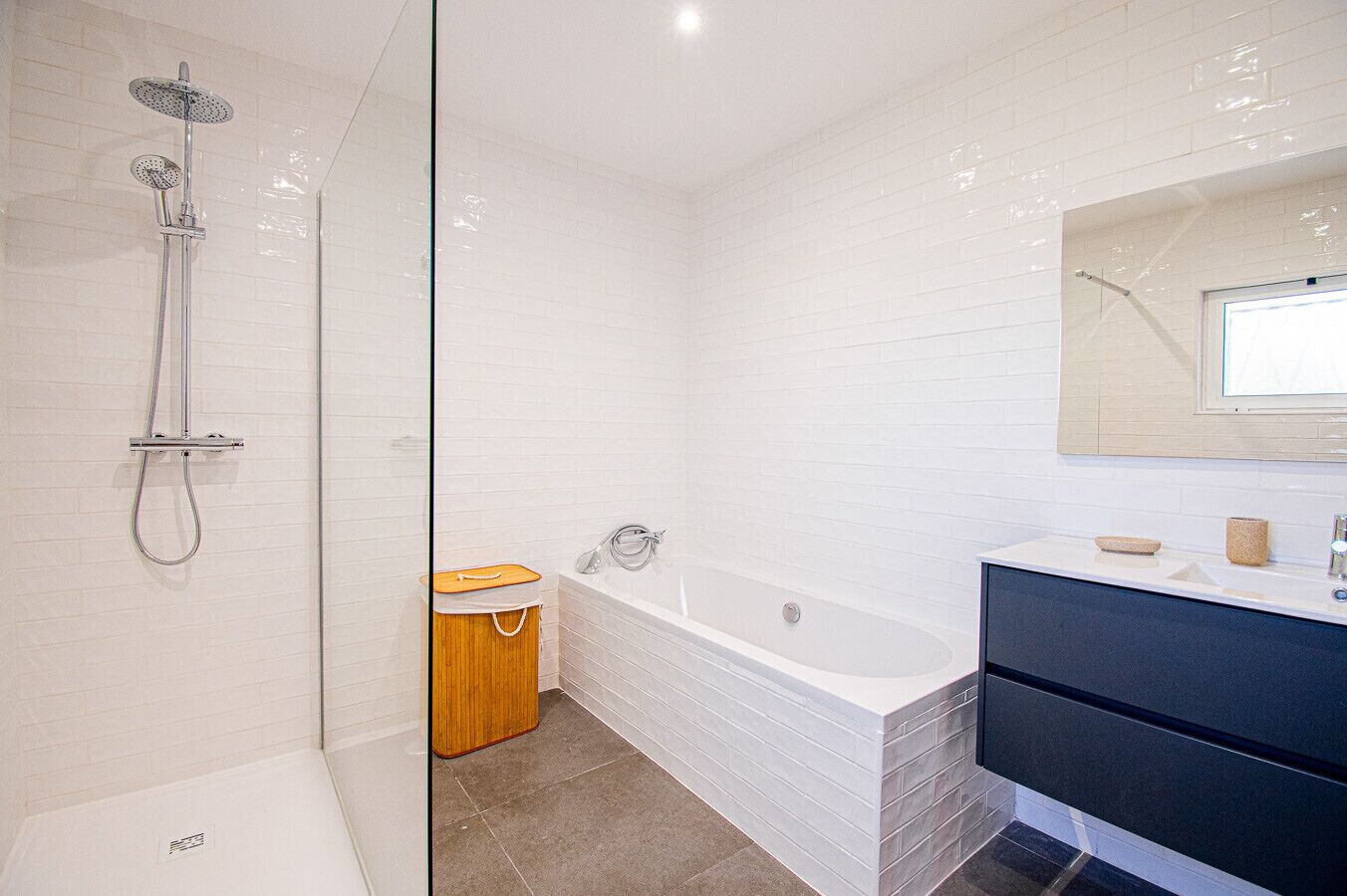 A modern bathroom with a shower, a bathtub, a vanity with a mirror, and a toilet.